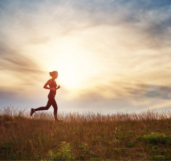 Young woman running on the field near seaside at sunset.